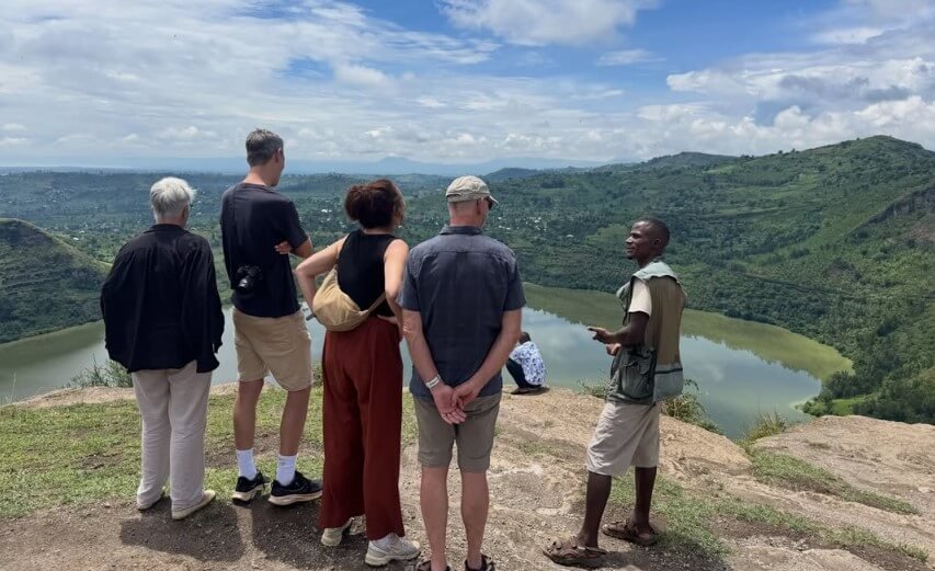 Aerial view of travelers standing at the edge of the Bunyaruguru Crater Lakes with deep green water in Uganda