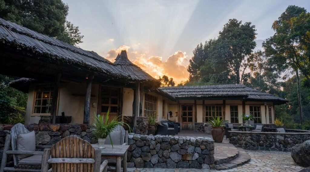 Exterior of a stone luxury lodge with a thatched roof at the base of the Mgahinga volcanoes.