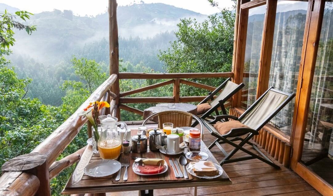 A breakfast table set on a private wooden balcony with a direct view of the dense rainforest foliage.