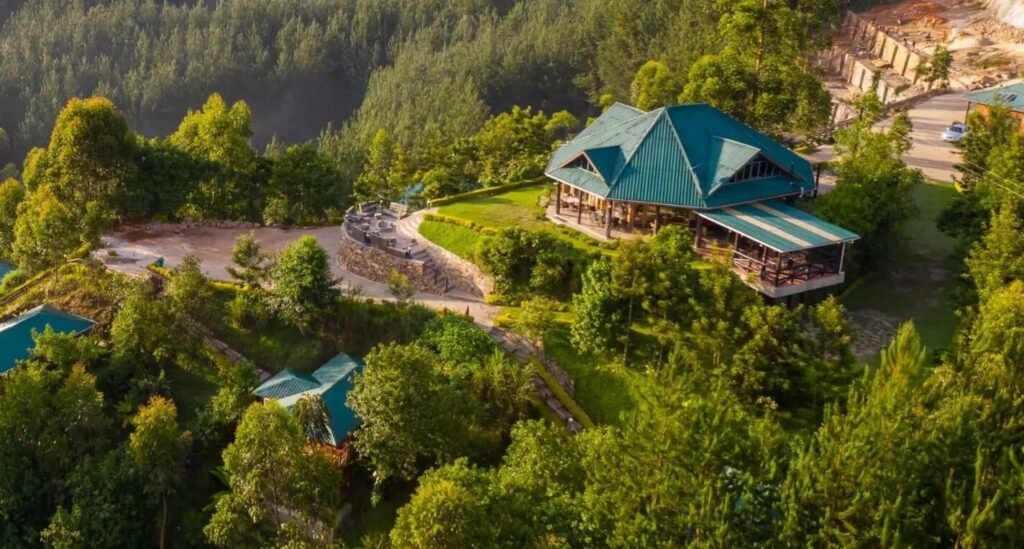 An aerial view of eco-lodges with green roofs tucked into the lush hillside of the southern Bwindi region.