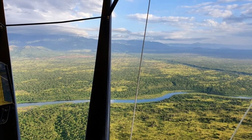 High-angle aerial view of the vast, green river valleys and volcanic landscapes of Virunga National Park.