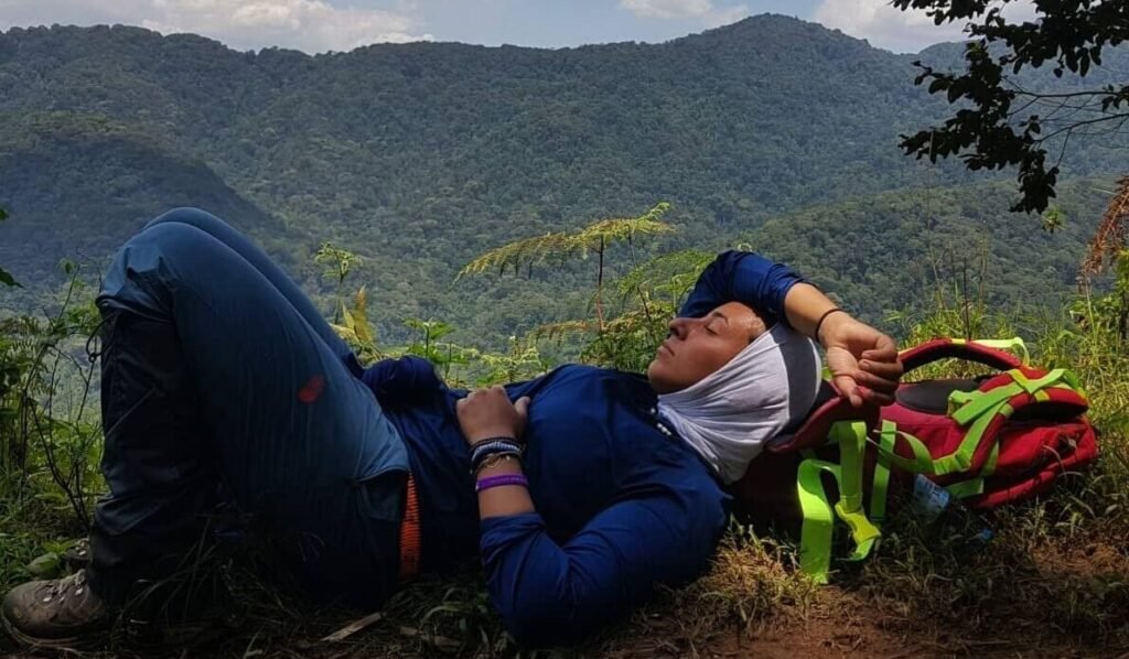 A traveler resting on a hillside with a panoramic view of the Buhoma sector valley.