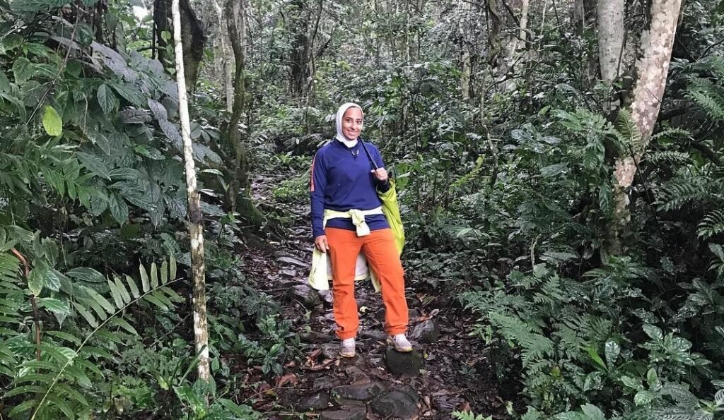 A hiker walking down a sun-dappled trail in the Buhoma sector of Bwindi.
