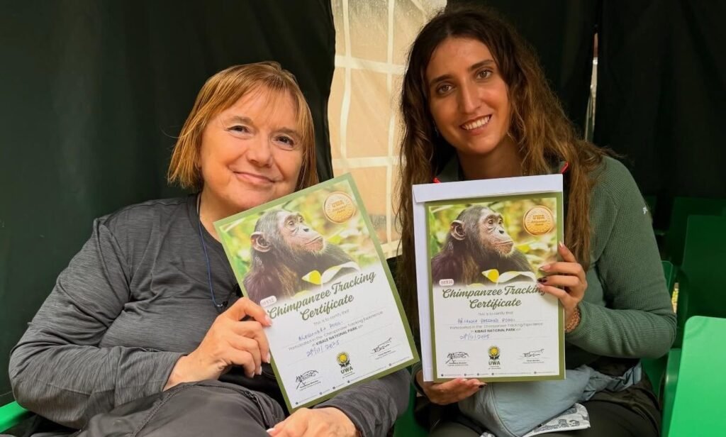 Two travelers holding their Kibale chimpanzee trekking certificates at Kanyanchu Visitor Centre, Uganda