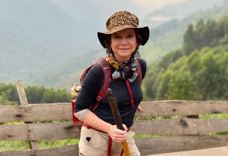 A female traveler wearing a sun hat and hiking gear, showing what to wear for gorilla trekking.