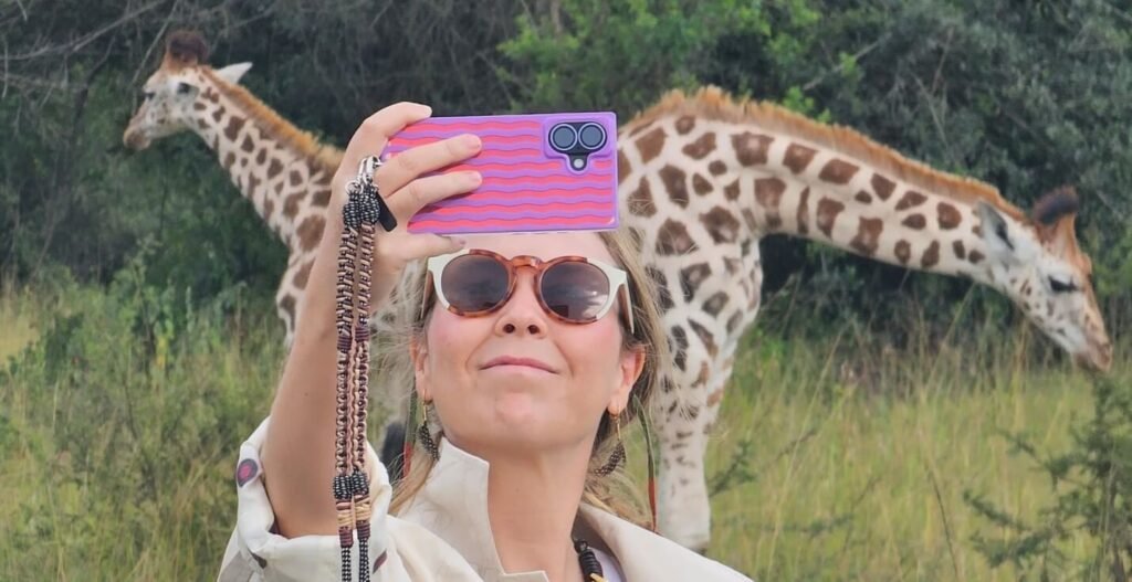 Tourist taking a selfie with a giraffe on a Uganda wildlife and safari tour