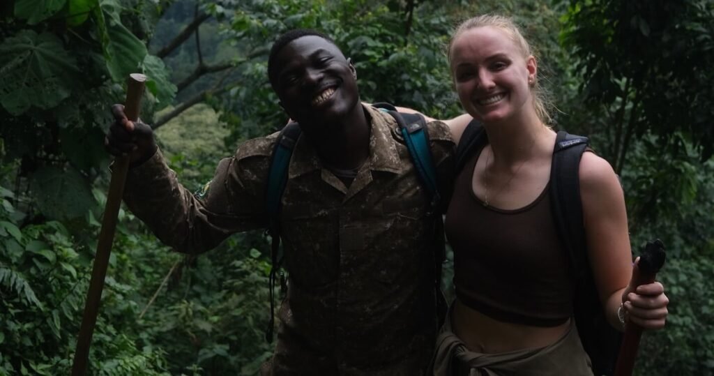 A local park ranger and a female hiker smiling together while resting on a steep jungle trail during the climb to find the gorillas.