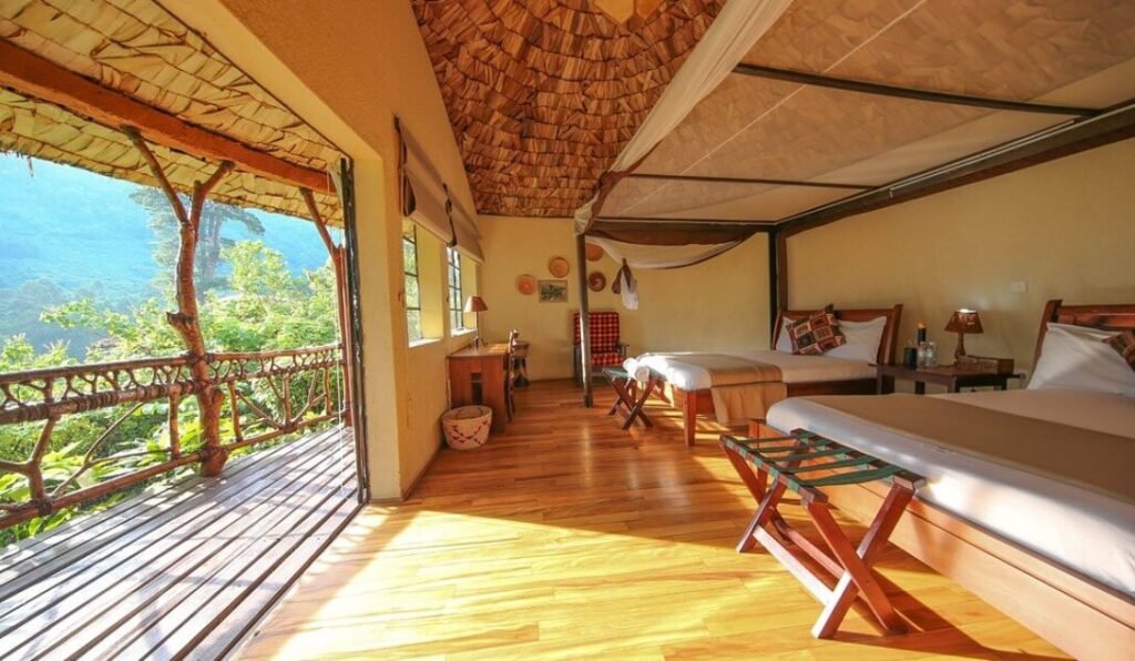 A spacious, high-end guest suite with polished wood floors, twin beds, and a large private balcony overlooking the forest.