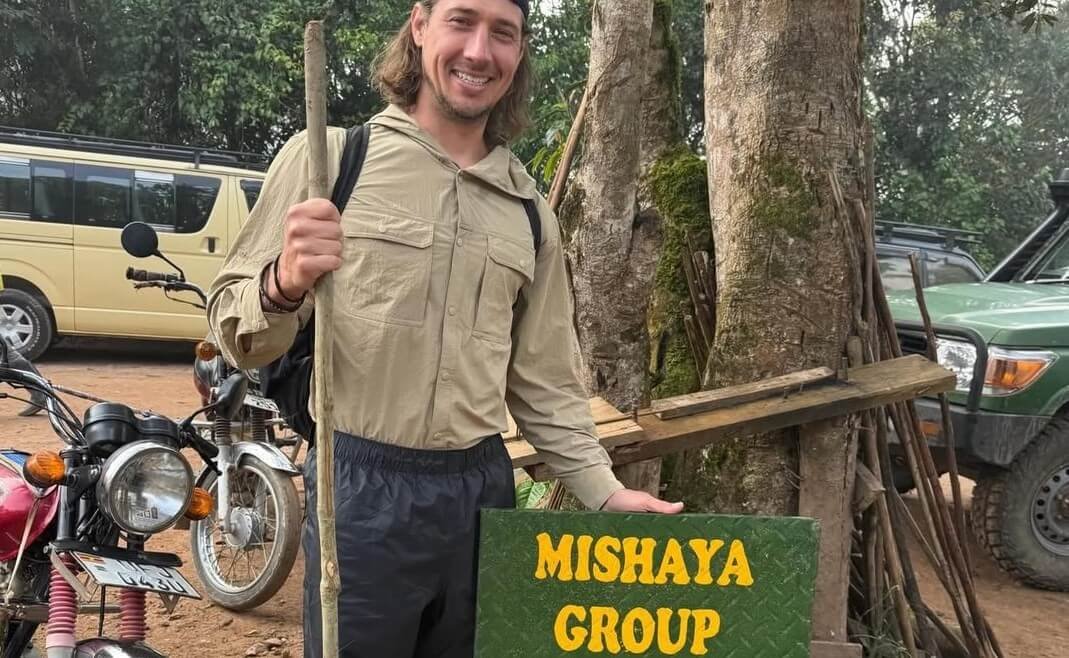 Traveler posing next to a sign for the Mishaya gorilla group in Bwindi.