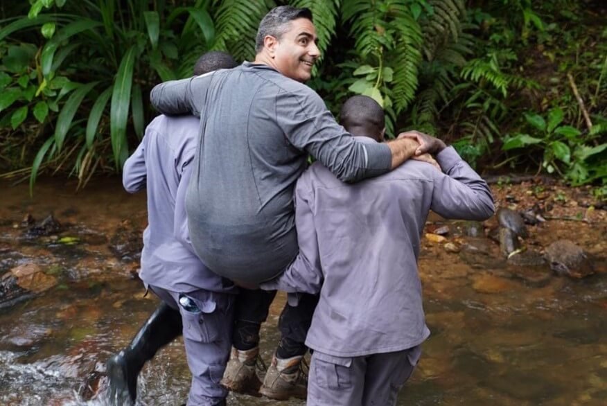 Porters using a traditional "sedan chair" to assist a traveler through difficult terrain, perfect for how hard is gorilla trekking.
