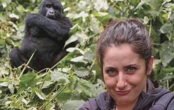 A female trekker observing a gorilla closely in the Bwindi rainforest.