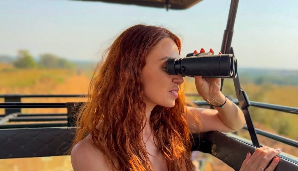 A female traveler using binoculars during a game drive in Murchison Falls National Park, Uganda