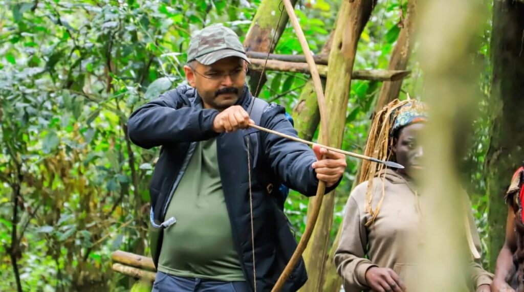 A tourist learning traditional archery from a Batwa guide in the Ugandan forest.