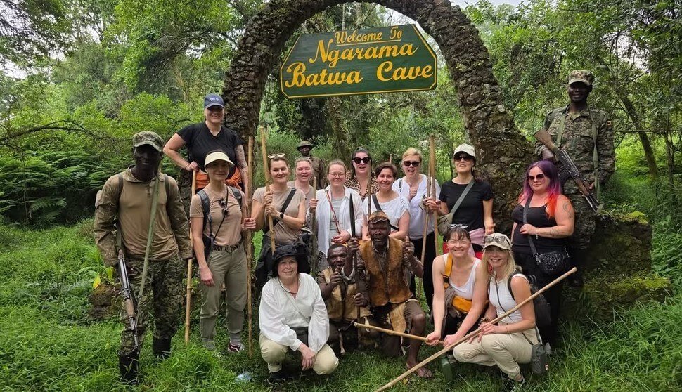 A group of hikers and guides crossing a wooden footbridge over a stream during a trek in Bwindi Impenetrable Forest.