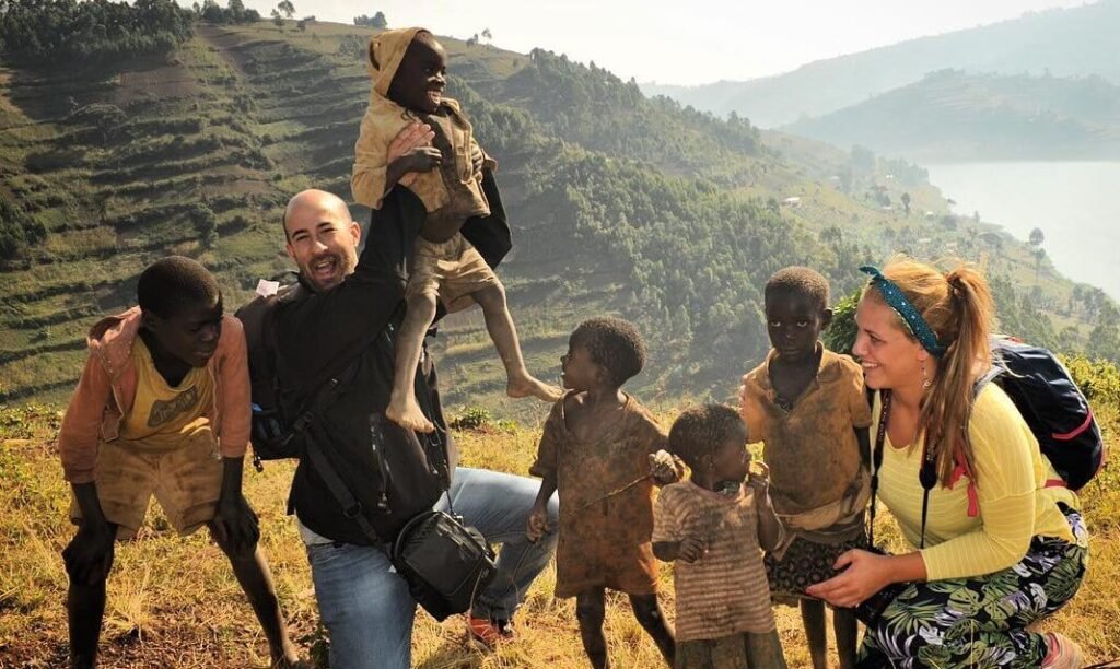 Travelers and local children standing together on a terraced hillside, highlighting the authentic community connections made during a safari.