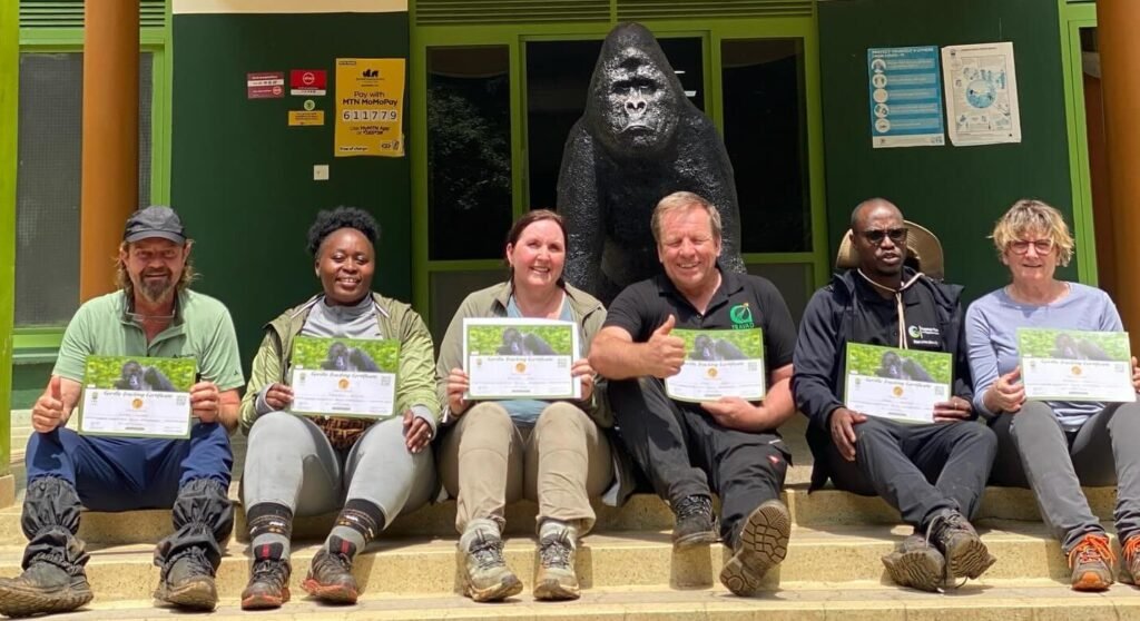 A group of international tourists sitting outside holding their official gorilla trekking certificates in Uganda.