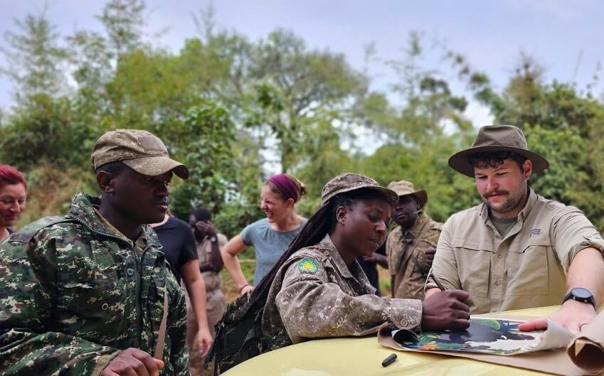 A group of travelers and guides reviewing a map during the morning briefing for gorilla trekking in Bwindi.