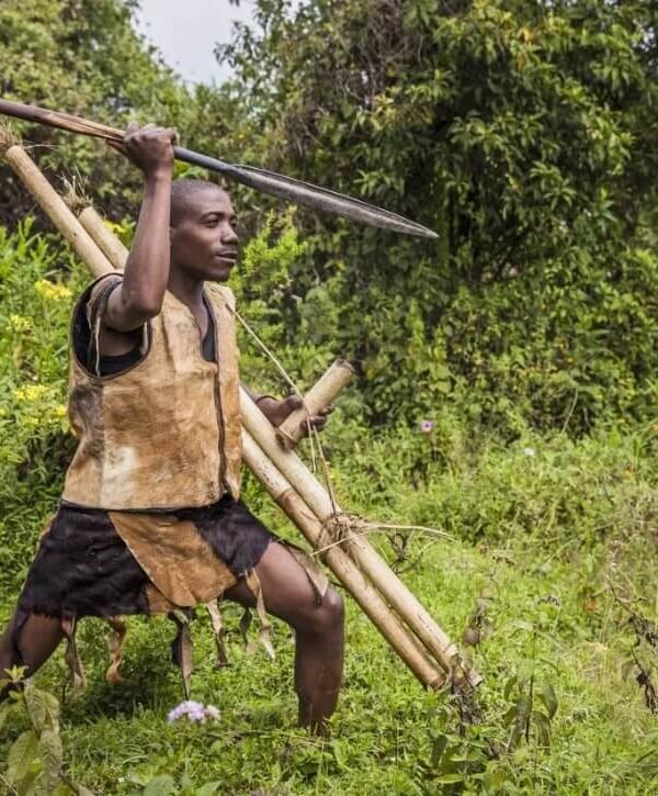 A Batwa man demonstrating traditional hunting techniques with a spear in the bush.