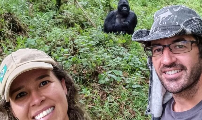 Close-up of happy trekkers with a mountain gorilla visible in the background forest.