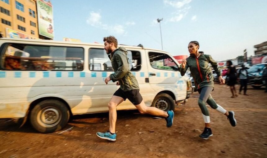Two travelers running alongside a white commuter taxi in the dusty, sunlit Old Taxi Park in Kampala, capturing the fast-paced energy of Uganda’s primary transport hub.