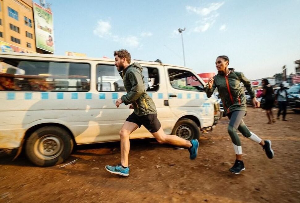Two travelers running alongside a white commuter taxi in the dusty, sunlit Old Taxi Park in Kampala, capturing the fast-paced energy of Uganda’s primary transport hub.