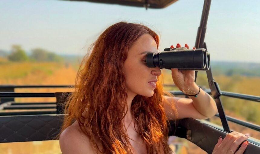 A female traveler using binoculars during a game drive in Murchison Falls National Park, Uganda