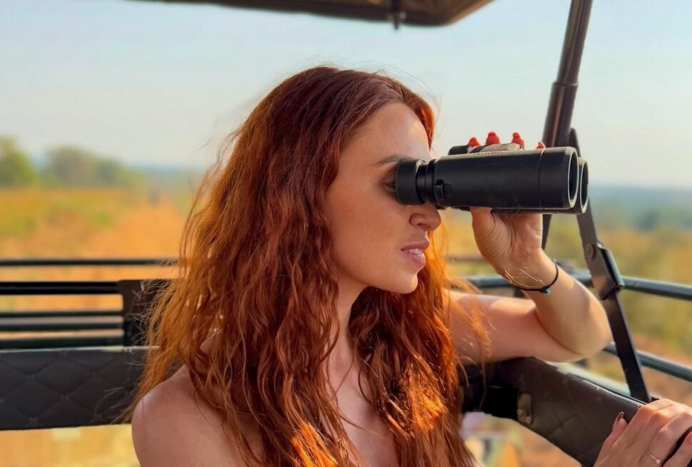 A female traveler using binoculars during a game drive in Murchison Falls National Park, Uganda