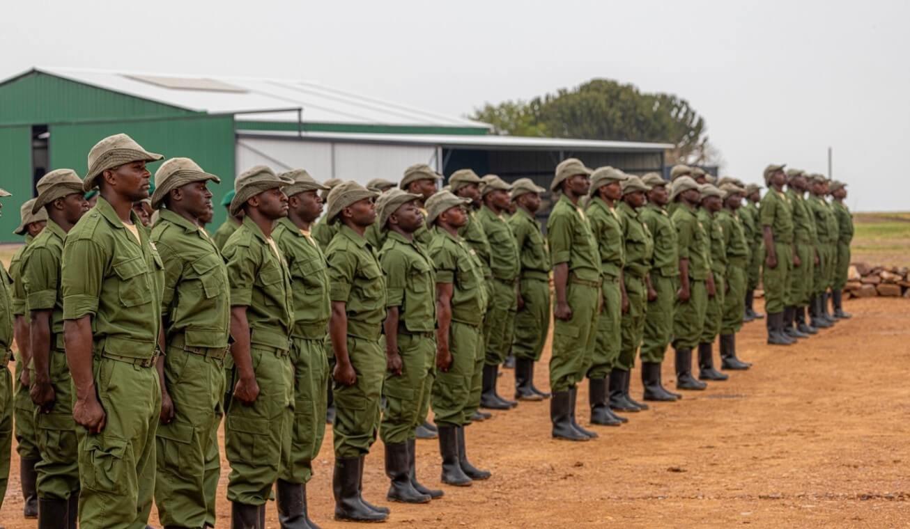 A disciplined line of Virunga National Park rangers in green uniforms standing at assembly during a morning briefing.